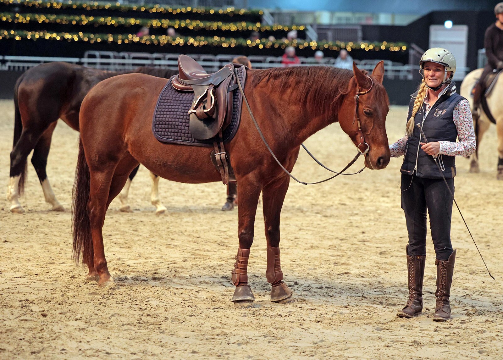 Yvonne Gutsche stseht neben ihrem gesatteltem Pferd in der Showarena